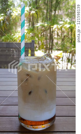 Coffee latte with a colorful straw in a medium glass in a table. 121598139