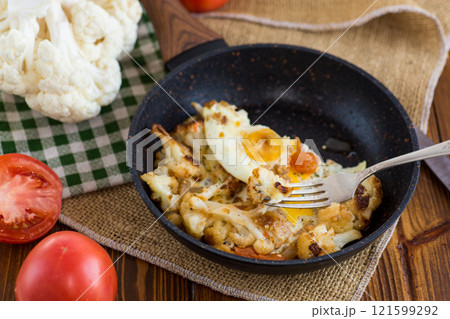 fried omelette with cauliflower and vegetables in a frying pan on a wooden table fried omelette with cauliflower and vegetables in a frying pan on a wooden table 121599292