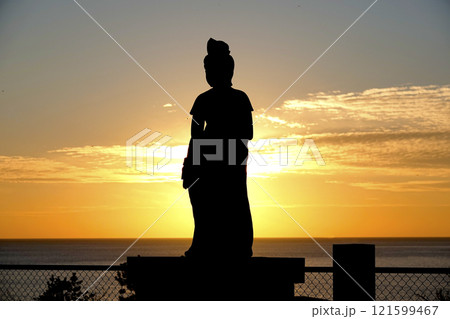 夕日に照らされてシルエットが浮き上がる聖観世音像 121599467