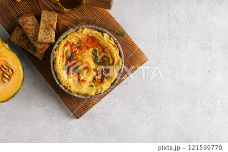 Homemade pumpkin chickpea hummus in a bowl on wooden board on light background. Top view, copy space for recepie Homemade pumpkin chickpea hummus in a bowl on wooden board on light background. Top view, copy space for recepie 121599770