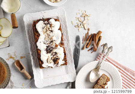 Spicy apple, nuts and oats loaf cake decorated with cream on a white plate, gluten free, top view Spicy apple, nuts and oats loaf cake decorated with cream on a white plate, gluten free, top view 121599799