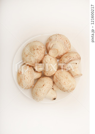 Fresh champignons on a white plate. Mushrooms on a white background. Fresh champignons on a white plate. Mushrooms on a white background. 121600217
