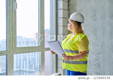 Technical profession woman in protective vest helmet working on construction Technical profession woman in protective vest helmet working on construction 121600316