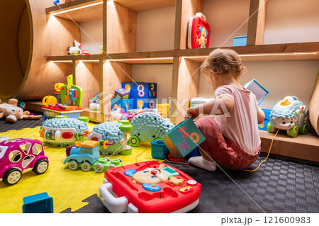 Toddler exploring educational toys in a lively playroom. Concept of early childhood development and creativity 121600983