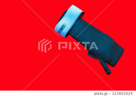 Medical tourniquet to stop bleeding. A device for slowing blood flow to the extremities, self-rescue, should be in everyone's first aid kit on red background Medical tourniquet to stop bleeding. A device for slowing blood flow to the extremities, self-rescue, should be in everyone's first aid kit on red background 121601024