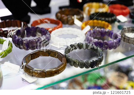 Assorted gemstone bracelets displayed on a glass shelf. Assorted gemstone bracelets displayed on a glass shelf. 121601725