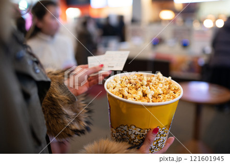 ポップコーンと映画の半券を持った女性の手元 ポップコーンと映画の半券を持った女性の手元 121601945