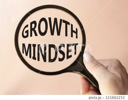 Growth Mindset symbol. Concept word Growth Mindset on magnifying glass. Beautiful pink background. Businessman hand. Business and Growth Mindset concept. Copy space 121602252