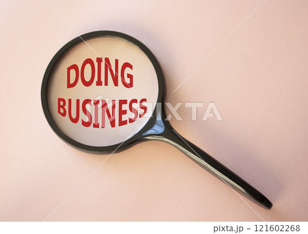 Doing Business symbol. Magnifying Glass with Concept word Doing Business. Beautiful pink background. Business and Doing Business concept. Copy space 121602268