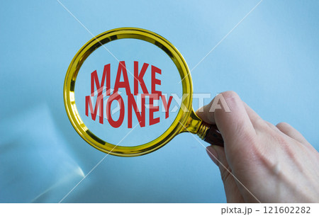 Make Money symbol. Magnifying Glass with Concept word Make Money. Businessman hand. Beautiful blue background. Business and Make Money concept. Copy space Make Money symbol. Magnifying Glass with Concept word Make Money. Businessman hand. Beautiful blue background. Business and Make Money concept. Copy space 121602282