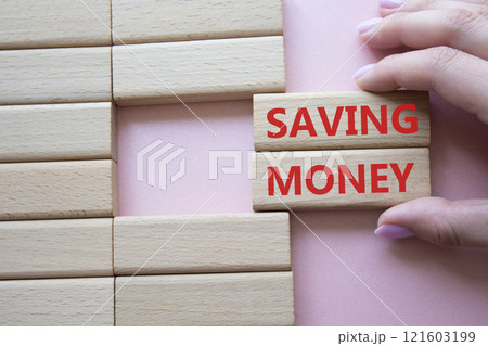 Saving Money symbol. Concept word Saving Money on wooden blocks. Businessman hand. Beautiful pink background. Business and Saving Money concept. Copy space 121603199