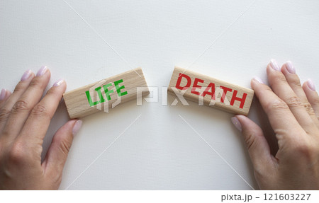 Life or Death symbol. Concept word Life or Death on wooden blocks. Businessman hand. Beautiful white background. Business and Life or Death concept. Copy space Life or Death symbol. Concept word Life or Death on wooden blocks. Businessman hand. Beautiful white background. Business and Life or Death concept. Copy space 121603227