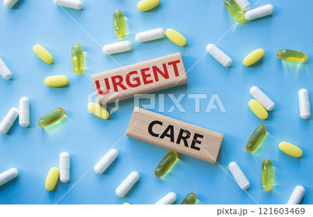 Urgent Care symbol. Concept word Urgent Care on wooden blocks. Beautiful blue background with pills. Medicine and Urgent Care concept. Copy space 121603469