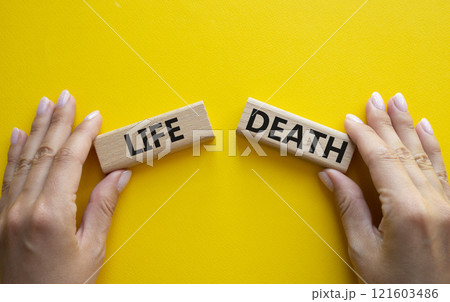 Life or Death symbol. Concept word Life or Death on wooden blocks. Businessman hand. Beautiful yellow background. Business and Life or Death concept. Copy space 121603486