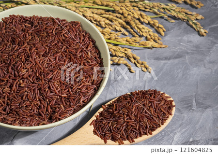 Nice red-rice in a bowl with spoon and ears of rice on wood Nice red-rice in a bowl with spoon and ears of rice on wood 121604825