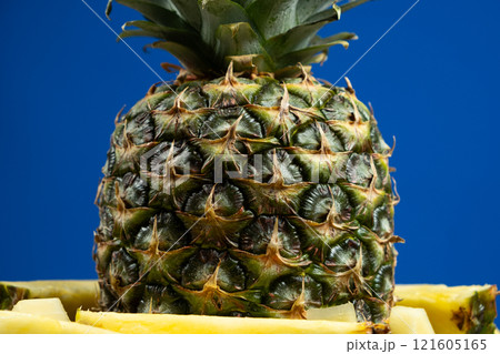 Whole pineapple and cut into pieces on a blue background close-up. 121605165