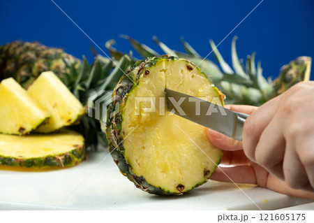 Hands cutting fresh pineapple fruit into pieces. 121605175
