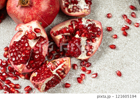 Pomegranate Seeds and Pomegranates on a Stone Gray Background Close-up Pomegranate Seeds and Pomegranates on a Stone Gray Background Close-up 121605194