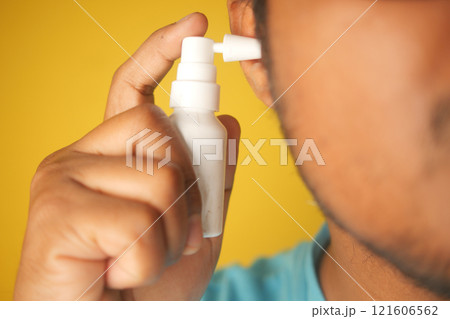 Close up of men using spray to remove earwax Close up of men using spray to remove earwax 121606562
