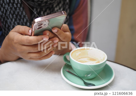 A person enjoys coffee and uses a smartphone in the afternoon A person enjoys coffee and uses a smartphone in the afternoon 121606636