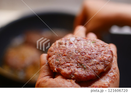 Freshly prepared, cooked burger patty held in hand, ready to enjoy 121606720