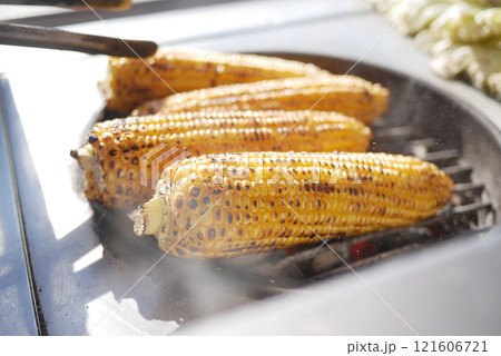 Grilling a delicious ear of corn on the cob during a sunny and warm summer day outdoors 121606721