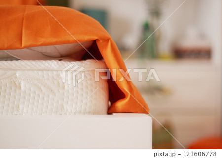 A Cozy Bedroom Corner Featuring a Bright Orange Bedspread for Comfort A Cozy Bedroom Corner Featuring a Bright Orange Bedspread for Comfort 121606778