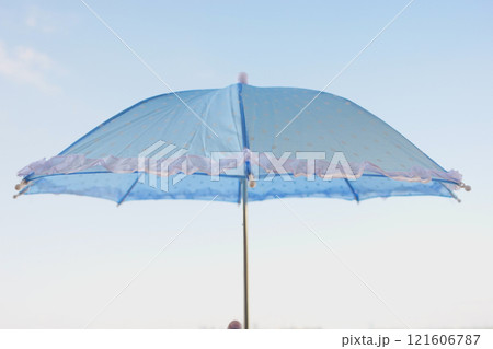 A Stylish Blue Umbrella with a Ruffled Edge Set Against a Clear Sky 121606787