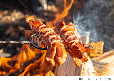 Roasted sausages on a stick over the open campfire. Outdoor food preparation. Roasted sausages on a stick over the open campfire. Outdoor food preparation. 121607280