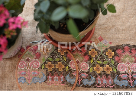 Cross-stitched traditional folk pattern on burlap fabric in embroidery hoop Cross-stitched traditional folk pattern on burlap fabric in embroidery hoop 121607858