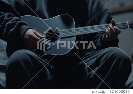 Person Playing Acoustic Guitar in Low Light Setting with Focus on Instrument and Hands 121608056