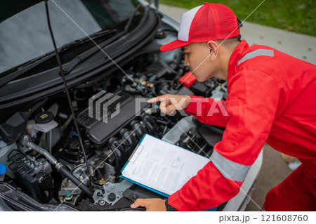 A Young Mechanic Conducts a Thorough Engine Inspection While Using a Checklist A Young Mechanic Conducts a Thorough Engine Inspection While Using a Checklist 121608760