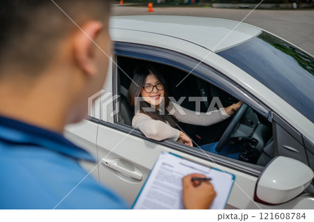 A Driving Test Assessment conducted between an Instructor and Student inside the Car 121608784