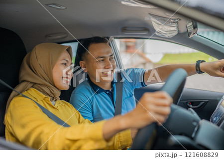 A Joyful and Happy Young Couple Are Enjoying a Fun Drive in a Modern Car 121608829