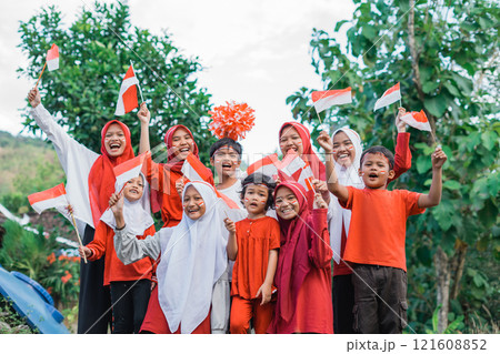 female supporters in headscarves and boys holding small Indonesian flags while supporting 121608852