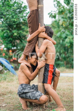 child squats as a pedestal during a betel nut climbing competition 121608858