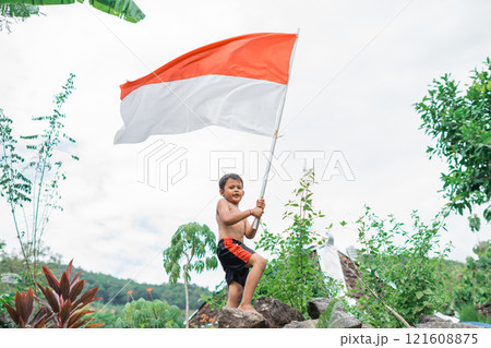 shirtless java boy raises the Indonesian flag while celebrating Indonesia's independence shirtless java boy raises the Indonesian flag while celebrating Indonesia's independence 121608875