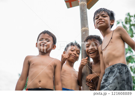 children smile at the camera under the pole of the betel nut 121608889