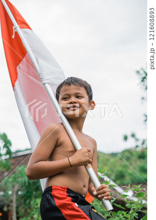 close up of shirtless smiling child carrying Indonesian flag during independence celebration close up of shirtless smiling child carrying Indonesian flag during independence celebration 121608893