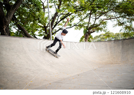 Skateboarder skillfully performing an array of exciting tricks in a modern skate park Skateboarder skillfully performing an array of exciting tricks in a modern skate park 121608910