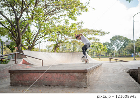 A skateboarder is performing an impressive trick in a lively urban skate park setting 121608945
