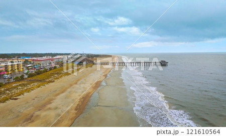 Scenic beach view with a pier and nearby coastal town 121610564
