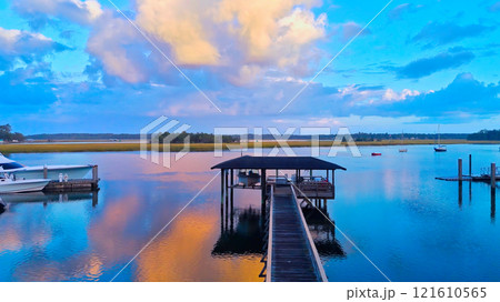 Tranquil Waterfront View with Dock and Colorful Sky 121610565