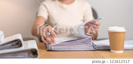 Asian woman reading financial report, female businesswoman sign contract or writing documents  paper at home or office late night. Overworked, work hard and business concept 121612517