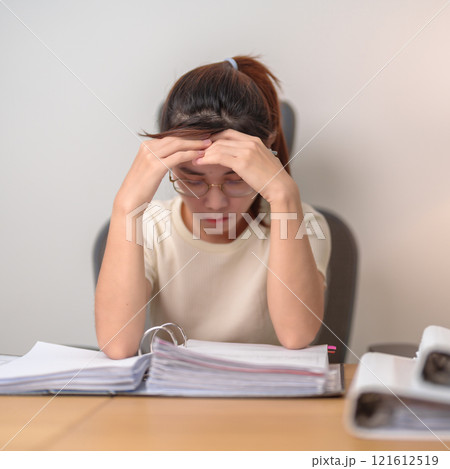 Asian woman having Tired and Stressed while working, female businesswoman having headache and Migraine at office, Exhausted woman with document folder stack at home late night. Overworked and Overtime Asian woman having Tired and Stressed while working, female businesswoman having headache and Migraine at office, Exhausted woman with document folder stack at home late night. Overworked and Overtime 121612519
