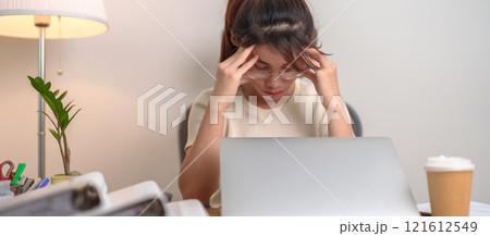 Stressed and Tired Asian woman while working, female businesswoman using laptop with headache, Migraine and Sleepy at office, Exhausted woman with computer at home late night. Overload and Overworked 121612549
