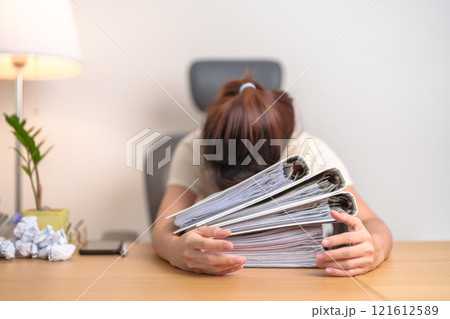 Stressed Asian woman having Tired and Sleepy while working, female businesswoman having headache at office, Exhausted woman with documents folder stack at home late night. Overworked and Overtime Stressed Asian woman having Tired and Sleepy while working, female businesswoman having headache at office, Exhausted woman with documents folder stack at home late night. Overworked and Overtime 121612589