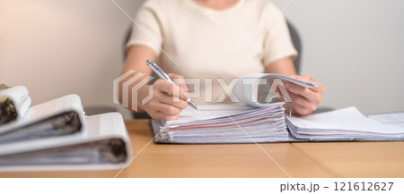 Asian woman reading financial report, female businesswoman sign contract or writing documents paper at home or office late night. Overworked, work hard and business concept Asian woman reading financial report, female businesswoman sign contract or writing documents paper at home or office late night. Overworked, work hard and business concept 121612627