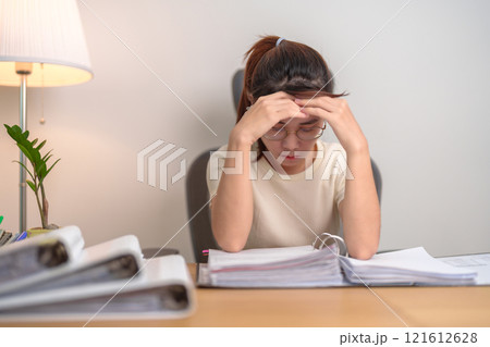 Asian woman having Tired and Stressed while working, female businesswoman having headache and Migraine at office, Exhausted woman with document folder stack at home late night. Overworked and Overtime Asian woman having Tired and Stressed while working, female businesswoman having headache and Migraine at office, Exhausted woman with document folder stack at home late night. Overworked and Overtime 121612628