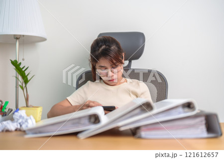 female businesswoman using smartphone at office, Stressed and Tired Asian woman while working, Exhausted woman with documents folder stack at home late night. Overload and Overworked female businesswoman using smartphone at office, Stressed and Tired Asian woman while working, Exhausted woman with documents folder stack at home late night. Overload and Overworked 121612657